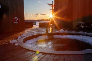 Outdoor cold plunge pool with chunks of ice on a wooden deck at Arctic Bath during golden sunset