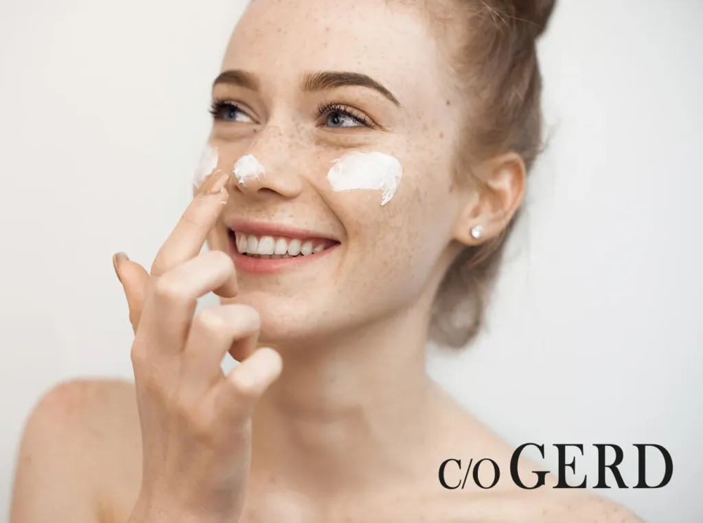 Smiling red-haired woman applying white cloudberry skincare cream to her face, c/o Gerd branding