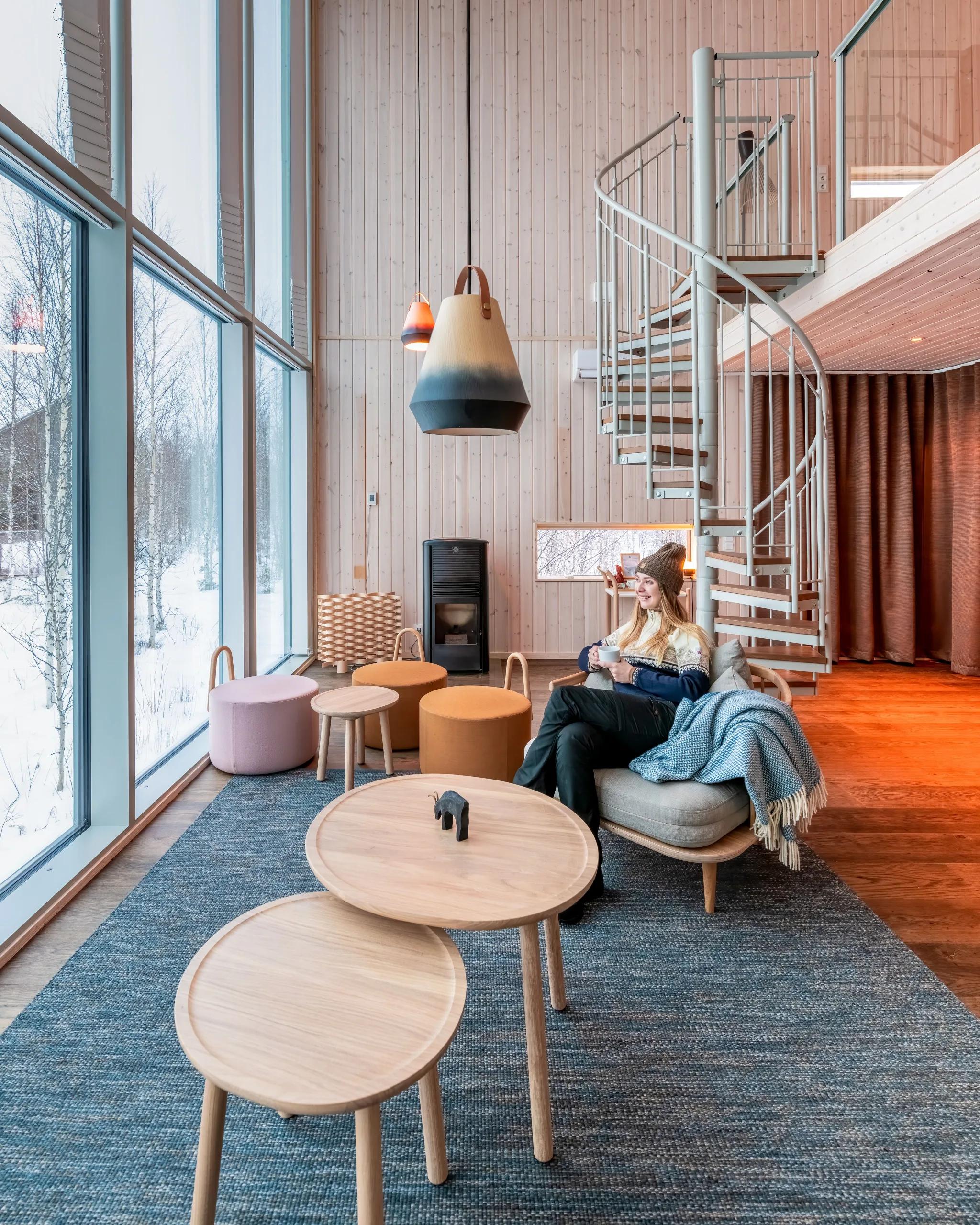 Guest enjoying a warm drink in an Arctic Bath cabin with views of a snowy forest