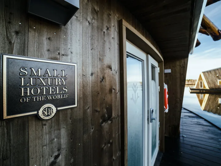 Small Luxury Hotels of the World plaque on a cabin wall with a water cabin reflected in the river beyond