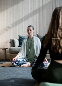 Guided meditation session with a woman seated cross-legged in a serene Scandinavian-style room