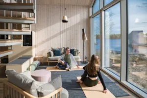 Two women practising yoga in a light-filled hotel suite overlooking the Lule River