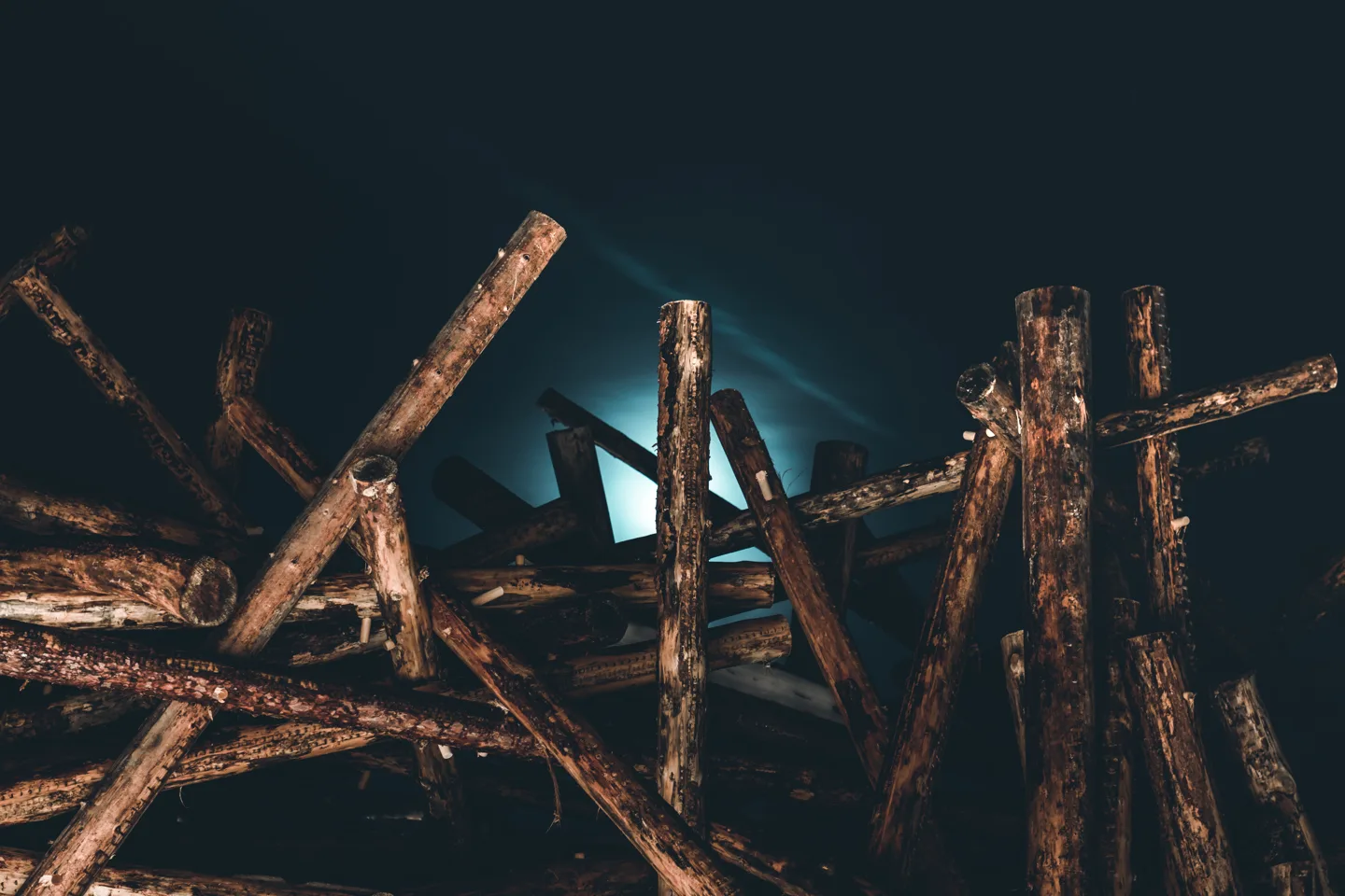 Nighttime close-up of Arctic Bath's crisscrossed log exterior silhouetted against cool blue interior light