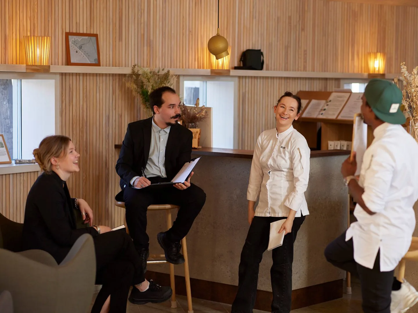 Arctic Bath staff in chef whites and suits meeting together in a wood-panelled interior