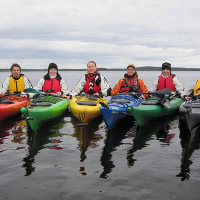 Kajaker i spegelblankt vatten med norrländsk skog runtom